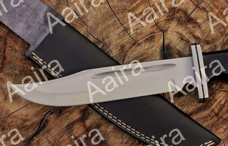 May include: A large, stainless steel knife with a black handle and a leather sheath. The blade is wide and curved, with a polished finish. The sheath is black with white stitching.