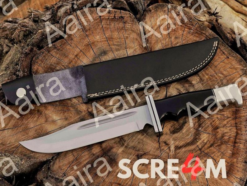 May include: A large, silver-bladed knife with a black handle and a black leather sheath. The knife has a silver guard and a curved blade. The sheath is stitched with white thread. The knife and sheath are on a wooden surface.
