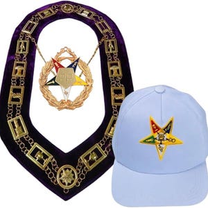Puede incluir: Un collar de terciopelo morado con eslabones dorados y un emblema central, junto con una gorra de béisbol azul claro con un emblema de estrella con acentos coloridos. El collar tiene un diseño decorativo.