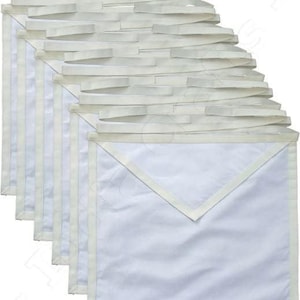 May include: A white fabric Masonic apron with a white collar and a white border. The apron is folded and stacked, showing the layers of fabric.