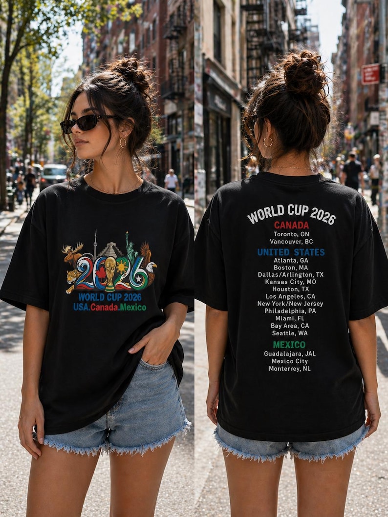 Pode incluir: Uma t-shirt preta com um gr&aacute;fico do World Cup 2026 na frente, incluindo um trof&eacute;u, s&iacute;mbolos nacionais e o texto USA, Canada, Mexico. As costas exibem o texto World Cup 2026 com uma lista das cidades-sede no Canad&aacute;, Estados Unidos e M&eacute;xico.