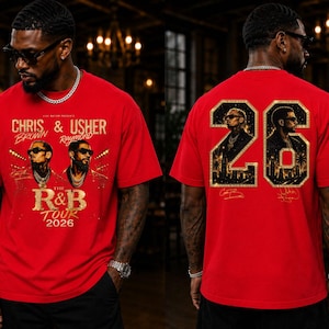 May include: A red short-sleeve t-shirt featuring a graphic print of Chris Brown and Usher with the text 'The R&B Tour 2026' on the front. The back displays the number '26' filled with portraits of the artists and a city skyline silhouette.