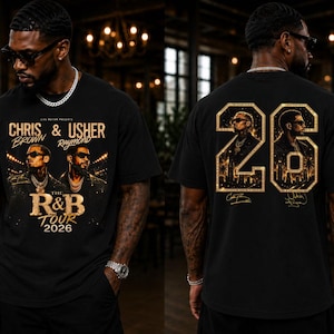 May include: A black t-shirt featuring a graphic print of Chris Brown and Usher. The front displays the text "Chris & Usher", "The R&B Tour 2026". The back features a large gold "26" with portraits of the artists and city silhouettes inside.