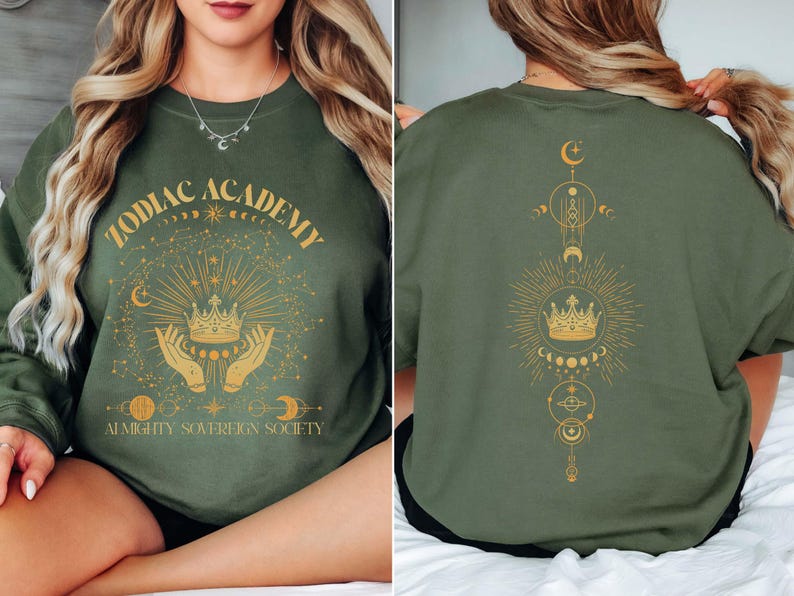 May include: Green sweatshirt with a gold graphic design featuring a crown, hands, stars, and moons. The text "Zodiac Academy Almighty Sovereign Society" is printed on the front of the sweatshirt.