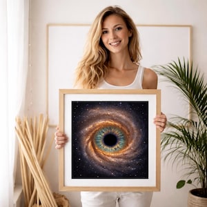 May include: A framed art print featuring a spiral galaxy design resembling an eye. The artwork showcases a black pupil surrounded by a teal iris, with swirling orange and brown cosmic elements. The print is set in a light-colored wooden frame.