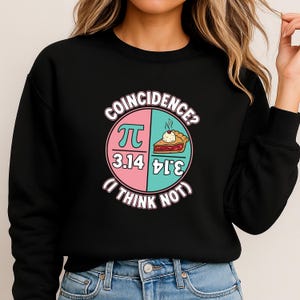 Peut inclure: Sweat-shirt noir avec un graphique représentant un diagramme circulaire. Le diagramme est divisé en sections roses et turquoise, avec le symbole pi et les chiffres 3,14. Le texte se lit "Coïncidence ? (Je ne pense pas)."