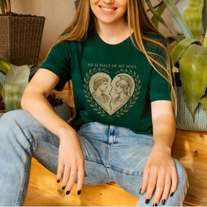 a woman sitting on a wooden floor wearing a green shirt