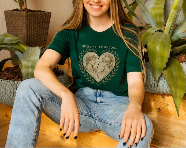 a woman sitting on a wooden floor wearing a green shirt