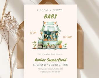 Op de afbeelding: Uitnodiging voor een babyshower met een aquarel illustratie van een marktkraam. De tekst luidt "Een lokaal geteelde baby is onderweg" en nodigt gasten uit om Amber Sumerfield op 23 oktober te eren.
