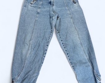 May include: Light blue denim jeans with zipper details on the sides and a button closure at the bottom of the legs.