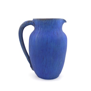 Può includere: Un'anfora in ceramica blu con una superficie testurizzata e un manico. L'anfora è un design classico con un corpo arrotondato e una bocca larga.