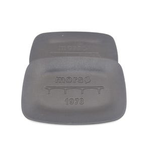 May include: A dark grey Morsø cast iron trivet. The trivet has a rectangular shape with rounded corners. The word "morsø" is printed on the top and bottom of the trivet. The year "1978" is printed on the bottom.