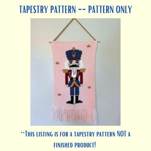 Può includere: Uno schema di arazzo rosa con un soldato Schiaccianoci con un cappello blu, una giacca rossa, bordi dorati e pantaloni blu. Lo schema è per un arazzo, non un prodotto finito. Il testo "TAPESTRY PATTERN -- PATTERN ONLY" è nella parte superiore dell'immagine. Il testo "**THIS LISTING IS FOR A TAPESTRY PATTERN NOT A FINISHED PRODUCT!**" è nella parte inferiore dell'immagine.