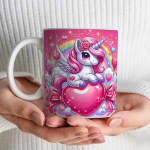 Può includere: Una tazza in ceramica rosa e bianca con un design di unicorno. L'unicorno è seduto su un cuore rosa con un arcobaleno sullo sfondo. La tazza ha un manico bianco.