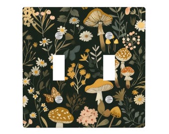 May include: A double light switch cover with a botanical design. The cover features mushrooms, flowers, and a butterfly on a dark green background. The design includes yellow, white, and brown elements.