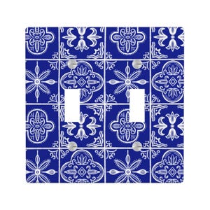 May include: A double light switch cover with a blue and white tile pattern. The design features a repeating pattern of floral and geometric shapes. The cover is made of a durable material and includes two switch openings and silver screws.