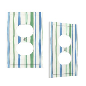May include: Two rectangular wall outlet covers featuring a vertical striped pattern in shades of blue, green, and white. Each cover has two circular openings for a standard duplex receptacle and a small centre hole for a mounting screw.