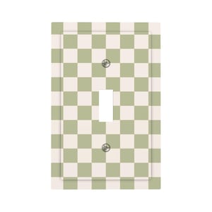 May include: A rectangular light switch wall plate featuring a repeating checkered pattern in sage green and off-white. The plate includes a central vertical rectangular cutout for a toggle switch and two circular holes for mounting screws.