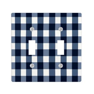 May include: A double light switch wall plate featuring a navy blue, light blue, and white buffalo plaid checkered pattern. The rectangular cover includes two vertical rectangular cutouts for switches and four silver metal mounting screws.