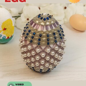 May include: A beaded egg with a pearl and blue bead design. The egg has a silver beaded top and is decorated with white pearls and blue beads. The text "BEADED EGG" is at the top of the image. A video tutorial is available.