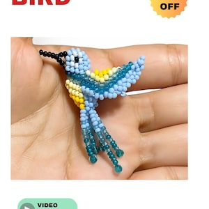 Puede incluir: Un pájaro hecho con cuentas azules, amarillas y turquesas. El pájaro tiene un pico y plumas de la cola negras. Las palabras "BEADED BIRD" están en texto rojo. Una pegatina amarilla con "50% OFF" está en la esquina superior derecha.