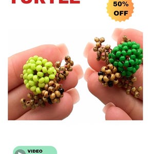 May include: Two beaded turtle figurines, one lime green and the other forest green, with brown beaded legs and heads. The word "BEADED" is above the word "TURTLE" in red. A yellow sticker says "50% OFF". A green button says "VIDEO Tutorial".