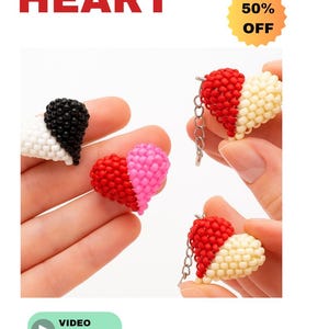Peut inclure: Porte-clés en forme de cœur perlés en rouge, rose, noir et blanc. Les porte-clés sont faits de petites perles et ont un motif de cœur. L'image comprend également le texte "BEADED HEART" et "50% OFF". Un tutoriel vidéo est également disponible.