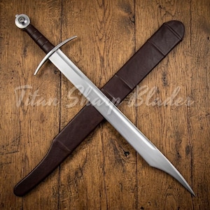 Könnte beinhalten: Ein mittelalterliches Schwert mit polierter Stahlklinge und einem braunen, lederummantelten Griff. Das Schwert liegt über einer braunen Lederscheide auf einem Holzgrund. Der Text "Titan Sharp Blades" ist sichtbar.