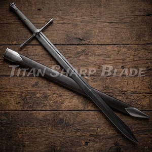 May include: A long, dark sword with a crossguard and a textured handle, resting on a wooden surface. The sword is accompanied by a black sheath with metal accents. The text "Titan Sharp Blade" is visible on the sheath.