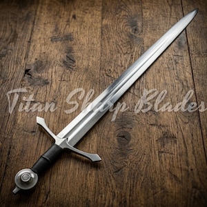May include: A long, silver sword with a black handle and a crossguard. The sword is lying on a wooden surface. The text "Titan Sharp Blades" is visible in the image.