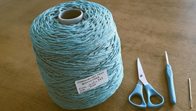 May include: A teal blue ball of cord, labeled "CORDONCINO THAY MISTOLUREX COL. 343 GR. 500", with a pair of scissors and a crochet hook.