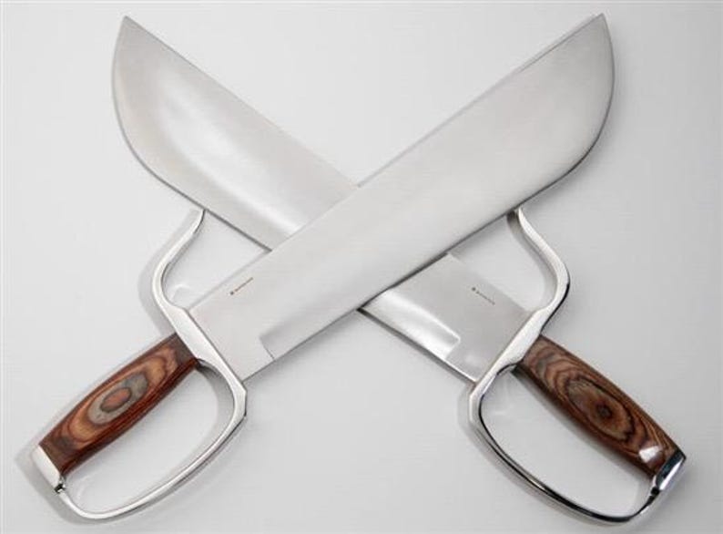 May include: A pair of silver-coloured, double-edged swords with wooden handles. The swords are crossed in an 'X' shape.