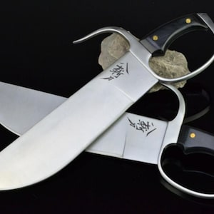May include: Two silver-colored Kung Fu swords with black handles. The swords are crossed and the blades have Chinese characters inscribed on them.