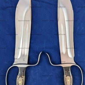 Peut inclure: Deux grands couteaux en acier poli avec des lames incurv&eacute;es et des manches en bois. Les manches ont une conception en boucle pour les doigts. Les lames mesurent environ 46 cm de long. Les couteaux sont pr&eacute;sent&eacute;s sur fond bleu.