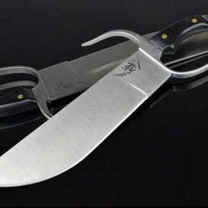 May include: A silver-colored double-edged sword with a black handle and a ring guard. The sword has a curved blade and a sharp point. The blade is engraved with Chinese characters.