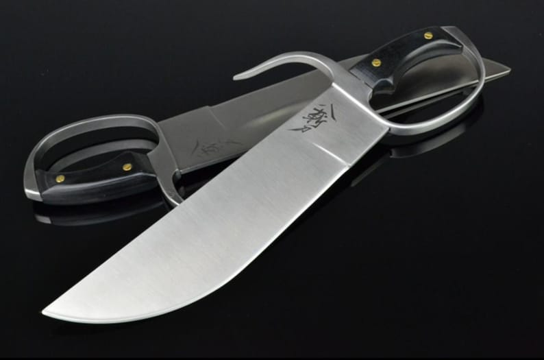 May include: A silver-colored double-edged sword with a black handle and a ring guard. The sword has a curved blade and a sharp point. The blade is engraved with Chinese characters.