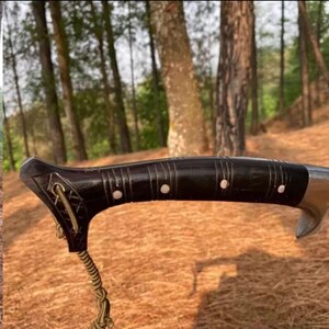 May include: Close-up of a black wooden handle with silver accents. The handle has a decorative rope attached to it.