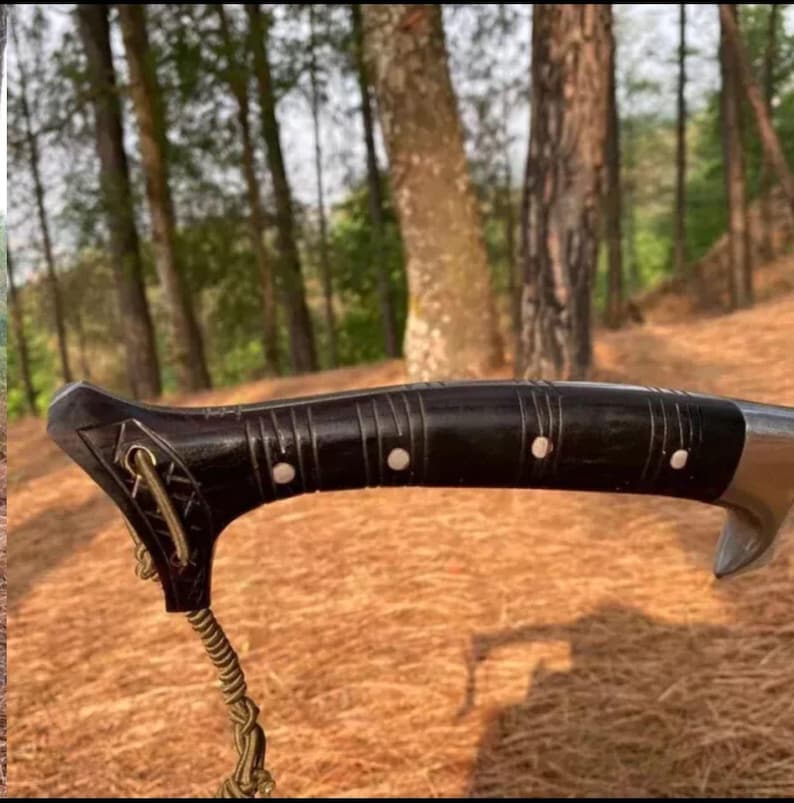 May include: Close-up of a black wooden handle with silver accents. The handle has a decorative rope attached to it.