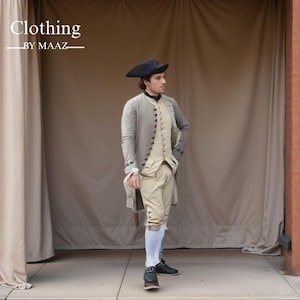 May include: A man wearing a historical costume, including a gray coat, beige vest, and breeches. The outfit is completed with a black hat and shoes. The text "Clothing BY MAAZ" is visible in the upper left corner.