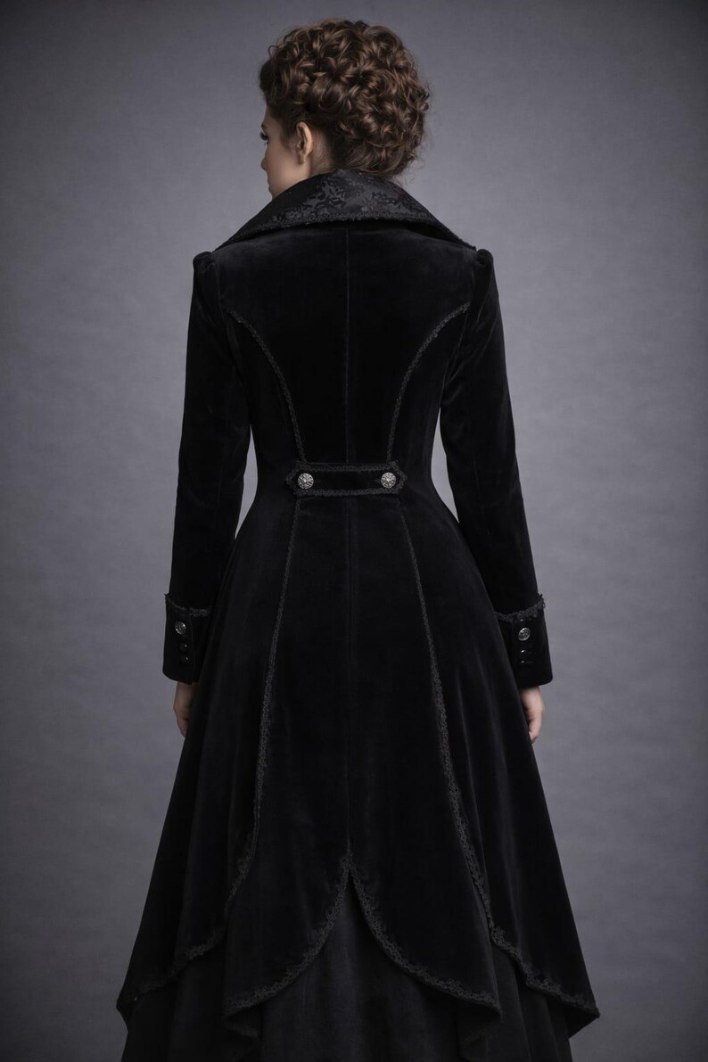 May include: A long, black velvet coat with a high collar and decorative buttons. The coat features intricate trim along the seams and cuffs, and a flared skirt. The back view showcases the coat's tailored design and elegant silhouette.