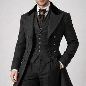 May include: A dark grey three-piece suit with a long coat. The coat has a black velvet collar and gold buttons. The waistcoat has gold buttons and is paired with a brown ascot.