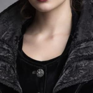 May include: A black velvet jacket with a layered collar and ornate button. The collar has a textured, patterned design. The jacket is buttoned up, and the fabric appears soft and luxurious. The overall style suggests a gothic or vintage aesthetic.