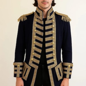 以下が含まれることがあります： 金色のトリムとボタンが付いた、ネイビーブルーのミリタリースタイルのジャケット。 ジャケットは、襟、袖口、前面に金色の装飾が施され、肩にはエポレットが付いています。 テキスト「Clothing BY MAAZ」は左上にあります。