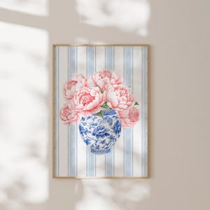 May include: A bouquet of pink peonies in a blue and white porcelain vase with a floral pattern. The vase is sitting on a blue and white striped background.