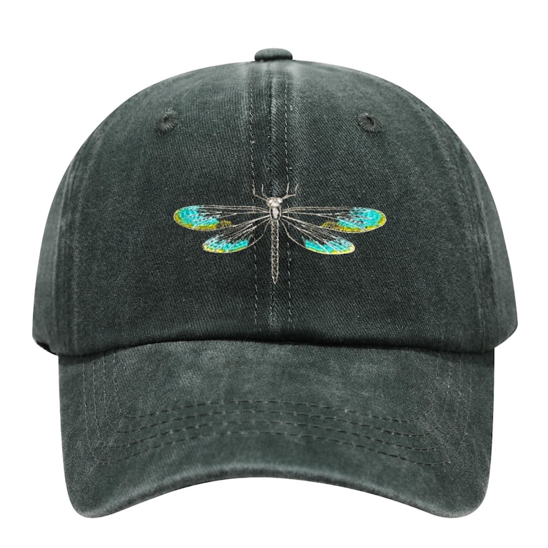 May include: A dark gray baseball cap featuring an embroidered dragonfly design. The dragonfly has teal and yellow wings and a silver body. The cap is made of a soft, textured fabric and has a curved brim.