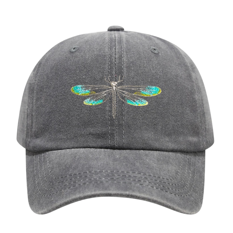 May include: A gray baseball cap featuring an embroidered dragonfly design. The dragonfly has teal and yellow wings and a silver body. The cap has a curved brim and a fabric strap closure.