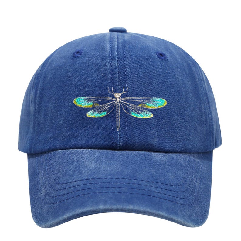 May include: A blue baseball cap with a dragonfly design. The dragonfly has teal and yellow wings and a silver body. The cap is made of a soft, textured material and has a curved brim.