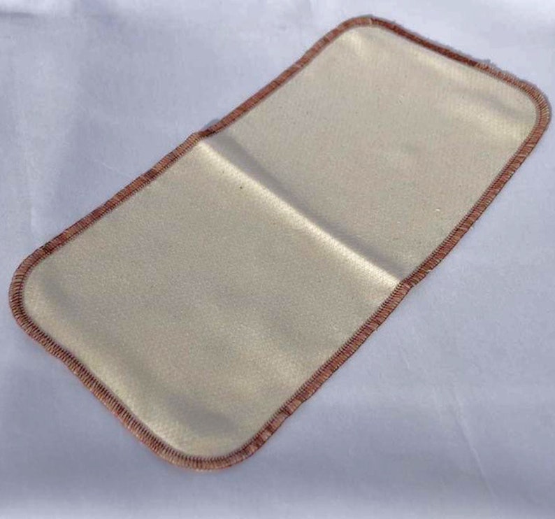 May include: A beige fabric insert with a brown stitched border. The insert is rectangular and has a smooth, even texture.