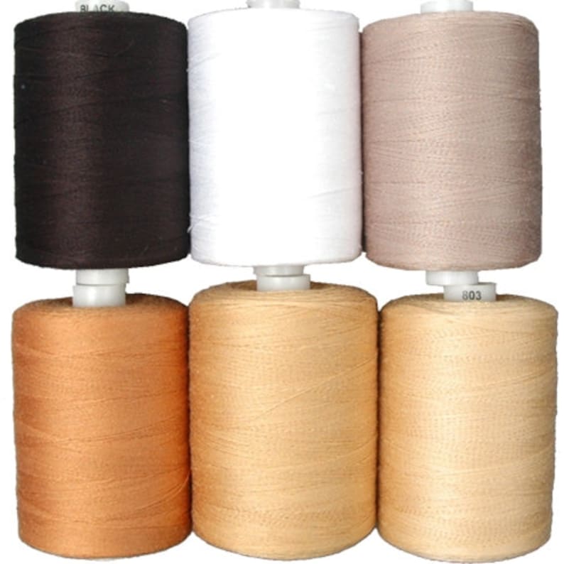 Puede incluir: Seis carretes de hilo en varios colores, incluyendo negro, blanco, beige y marr&oacute;n. Los carretes est&aacute;n dispuestos en dos filas de tres.