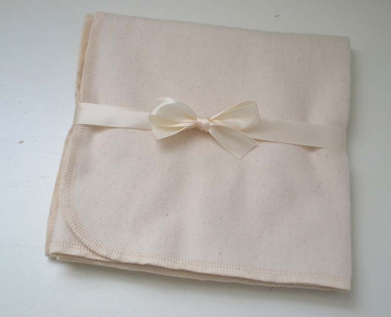 May include: A cream-colored blanket with a satin ribbon tied in a bow.